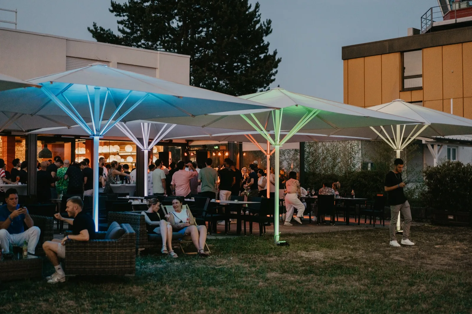 Außenbereich des Common Sense Event Space mit beleuchteten Schirmen im Abendlicht